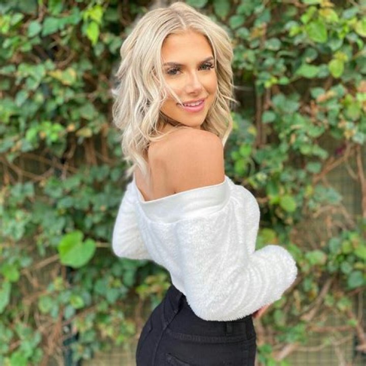 Alyssa Hyde dressed in black with leather tights standing in front of a black Range Rover.