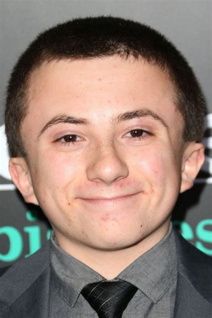 Picture of Atticus Shaffer posing by wearing a green outfit.